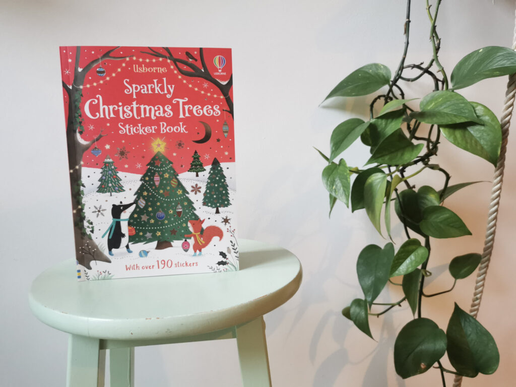 A Sparkly Christmas Tree activity book on a green stool with a green plant to the right