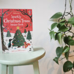 A Sparkly Christmas Tree activity book on a green stool with a green plant to the right