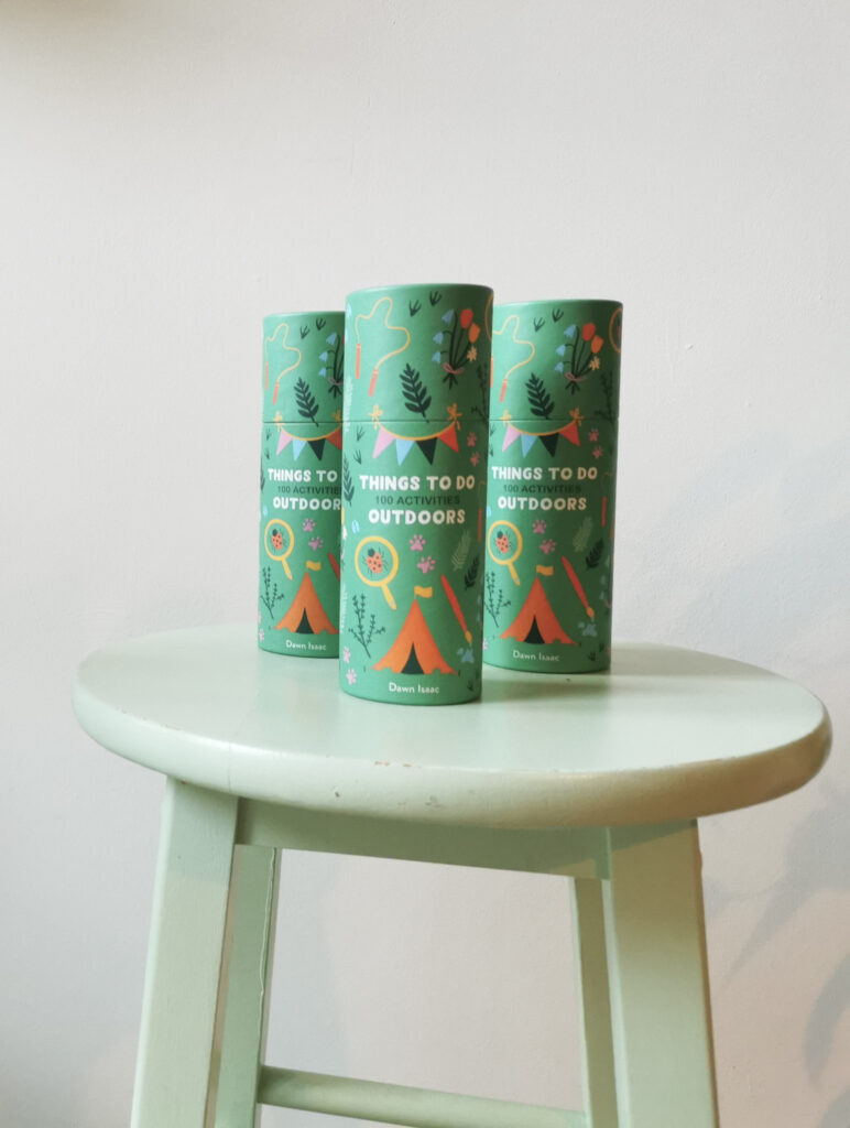 A green tube of things to do outdoors on a green stool with a green plant to the right